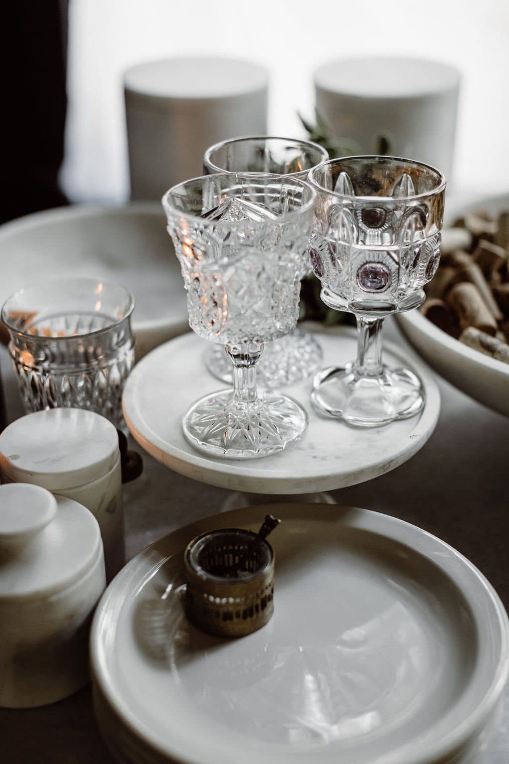 Stacked cut-crystal glasses and white plates ready for service